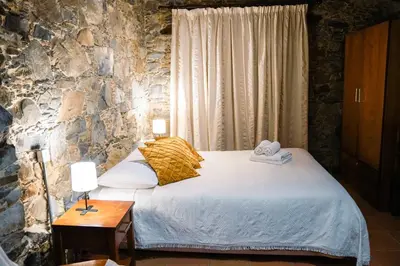 a bedroom with a bed and a stone wall at Archontiko Rousias in Nicosia