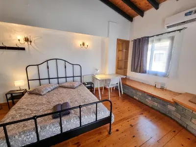 a bedroom with a bed and a table and a window at Mountains Retreat Rooms & Suites in Ayios Theodhoros