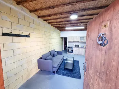 a living room with a couch and a brick wall at Mountains Retreat Rooms & Suites in Ayios Theodhoros