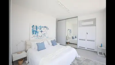 a white bedroom with a large white bed with blue pillows at Protaras Olivine Villa Ol3 in Protaras