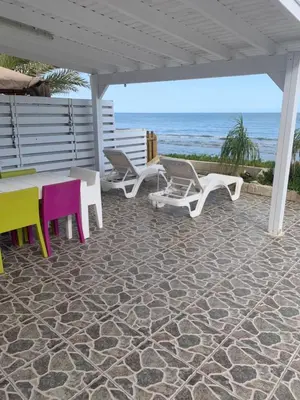 a patio with chairs and a table on the beach at Seafront Beach House in Meneou