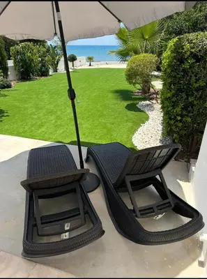 two chairs sitting under an umbrella on a patio at Beach Front Periyiali Gardens in Pervolia