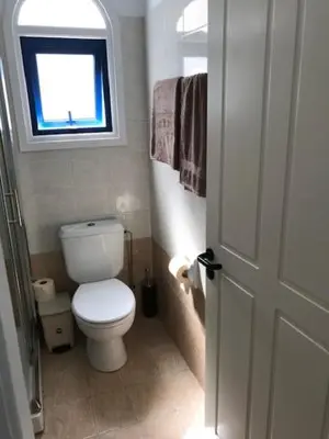 a bathroom with a white toilet and a window at Beach Front Periyiali Gardens in Pervolia
