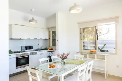 a white kitchen with a table and chairs and a window at Protaras Artisan Seafront Villa 1 in Protaras