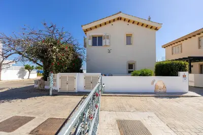 a white house with a fence in front of it at Protaras Artisan Seafront Villa 1 in Protaras