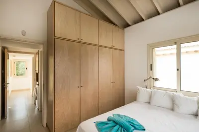 a bedroom with a white bed and wooden cabinets at Protaras Artisan Seafront Villa 7 in Protaras