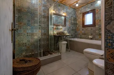 a bathroom with a shower and a toilet and a tub at Rozana House in Silikou