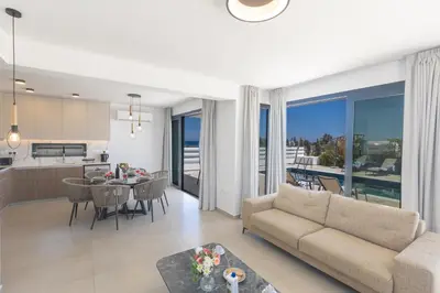 a living room and kitchen with a couch and a table at Trinity Villa in Paralimni