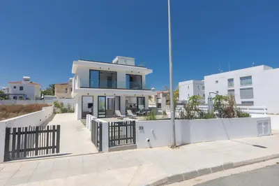 a white house with a fence in front of it at Trinity Villa in Paralimni