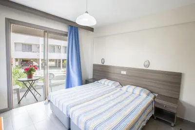 a bedroom with a bed and a balcony with a table at Ayia Napa Holiday Apartment So4 in Ayia Napa