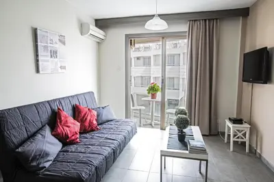 a living room with a black couch with red pillows at Ayia Napa Holiday Apartment So6 in Ayia Napa