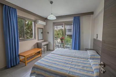 a bedroom with a bed and a desk and windows at Ayia Napa Holiday Apartment So9 in Ayia Napa