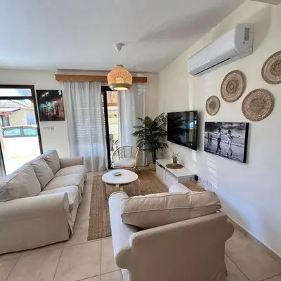 a living room with couches and a table and a tv at Pervolina countryside by the sea in Pervolia
