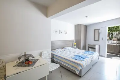 a white bedroom with a bed and a table at Ayia Napa Holiday Apartment Ss1 in Ayia Napa