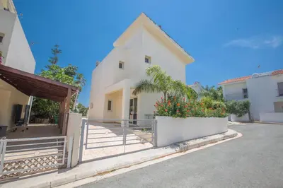 a white house with a fence and flowers in a yard at Protaras Delfini Villa Dv8 in Protaras