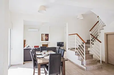 a dining room with a table and chairs and a staircase at Protaras Delfini Villa Dv5 in Protaras