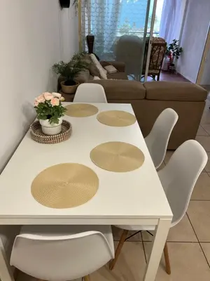 a table with four chairs and a white table with flowers on it at Carisa Holiday rooms in Larnaka