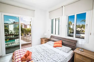 a bedroom with a bed and a balcony with windows at Villa Mesogeios ME25 in Protaras