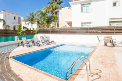 a swimming pool with chairs next to a building at Villa Mesogeios ME25 in Protaras