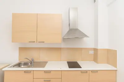 a kitchen with wooden cabinets and a sink at Flora Hotel Apartments in Protaras