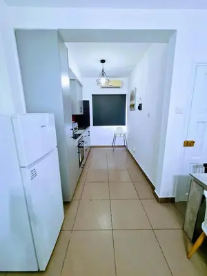 a kitchen with white walls and a tiled floor at Ayia Anna Apartment in Ayia Napa