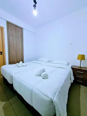a large white bed in a room with a light at Ayia Anna Apartment in Ayia Napa