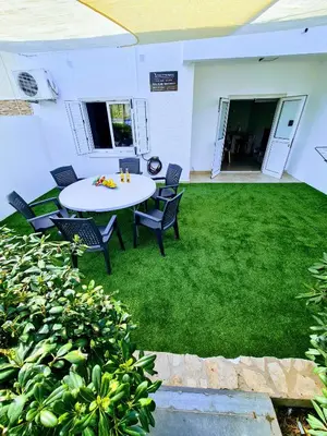 a patio with a table and chairs on the grass at Ayia Anna Apartment in Ayia Napa