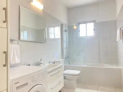 a white bathroom with a tub and a toilet and a sink at Phaedrus Living Down Town Flat Nestoras 301 in Limassol