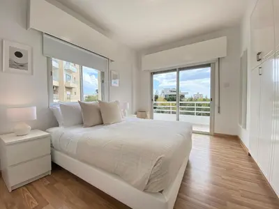 a bedroom with a white bed and a large window at Phaedrus Living Down Town Flat Nestoras 301 in Limassol