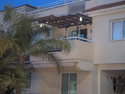 a white building with a balcony and a palm tree at Andros Apt 2 Bed, Free Wi-fi, Safe, Complex Pool in Paralimni