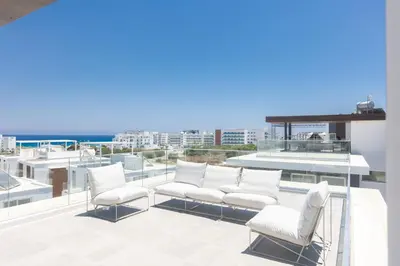 a balcony with white chairs and a view of the ocean at Protaras Olivine Villa Ol9 in Protaras