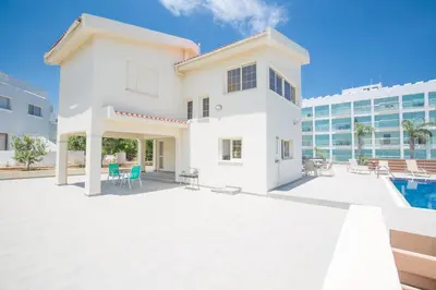 a white house with a pool and a building at Protaras Holiday Villa Dv16 in Protaras