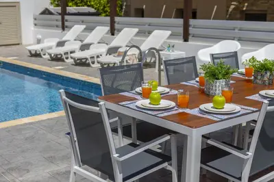 a dining table and chairs next to a pool at Protaras Sunrise Beach Villa 2 in Protaras