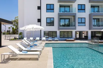 a swimming pool with lounge chairs and a building at The Quality Lodge - Self Check-in in Voroklini