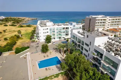 an aerial view of a building and the ocean at Coralli Spa Resort Protaras Stylish 1 Bedroom apartment in Protaras