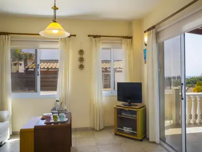 a living room with a tv and large windows at Protaras Villa Amber By The Sea in Protaras