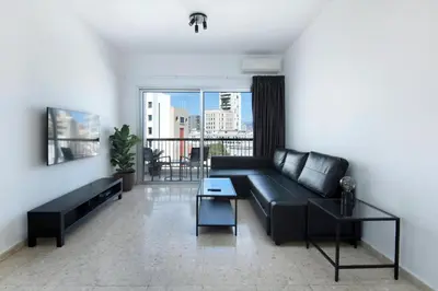 a living room with a black couch and a balcony at Urban Condo Promitheos in Nicosia