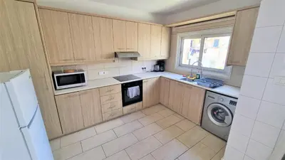a kitchen with wooden cabinets and a washer and dryer at Coastal Getaway: 2 Apartments for up to 14 guests! Light-flooded and Spacious in Larnaka