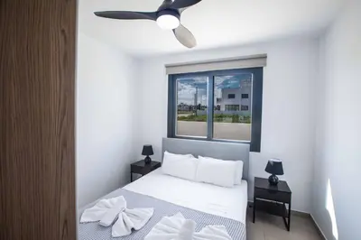 a bedroom with a white bed with a ceiling fan at Protaras Holiday Villa TI39 in Paralimni