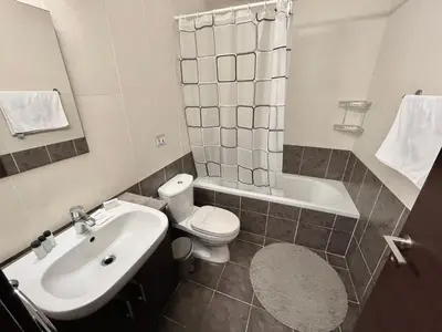 a bathroom with a sink and a toilet and a tub at Mythical Sands Holiday Apartment in Paralimni