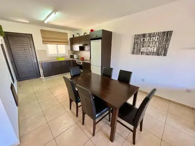 a kitchen and dining room with a wooden table and chairs at Mythical Sands Holiday Apartment in Paralimni