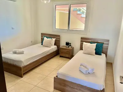two beds in a room with a window at Mythical Sands Holiday Apartment in Paralimni