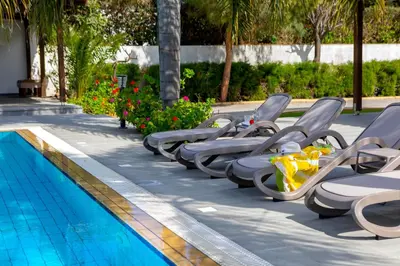 a row of lounge chairs next to a swimming pool at Cape Greco Palm Trees Villa in Ayia Napa