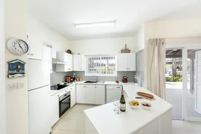 a kitchen with white cabinets and a clock on the wall at Cape Greco Palm Trees Villa in Ayia Napa