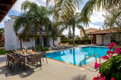 a patio with a table and chairs next to a swimming pool at Cape Greco Palm Trees Villa in Ayia Napa