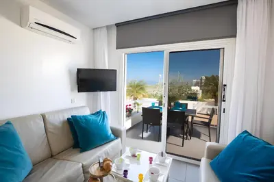 a living room with a couch and a view of a patio at Sun & Sea Seaview Apartment in Protaras