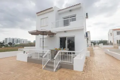 a white house with an umbrella on the roof at Sun & Sea Seaview Apartment in Protaras