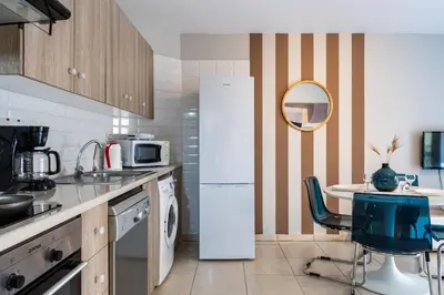 a kitchen with a refrigerator and a table with a chair at Gitane 1-Bedroom Apartment in Larnaca in Larnaka