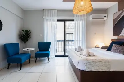 a bedroom with a bed and two blue chairs at Gitane 1-Bedroom Apartment in Larnaca in Larnaka