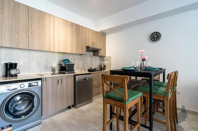 a kitchen with a washing machine and a table with chairs at Crystal 2-Bedroom Apartment in Larnaca in Larnaka